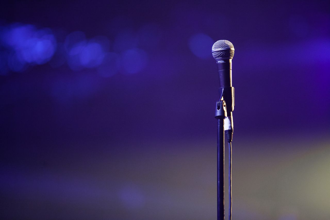 About A dynamic photo of a microphone on a stand against a vibrant purple backdrop, suitable for music themes.