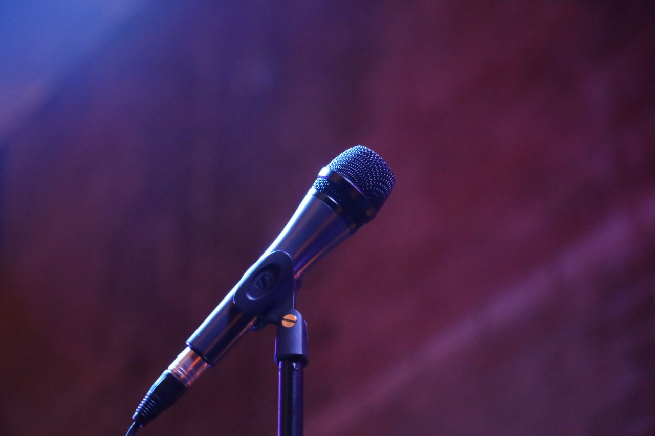 About A microphone on a stand against a blurred background, perfect for music or event themes.